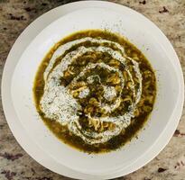 Spinach soup with walnuts in a white plate on the table photo