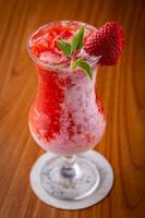 Strawberry smoothie in a glass on a wooden table. photo