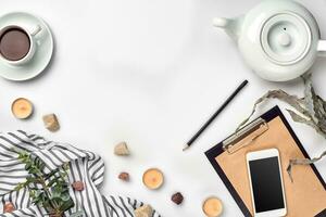 Notepad with pen and cup of tea on white table. Working space. Handmade. Top view, flat lay. photo