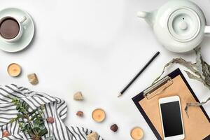 Notepad with pen and cup of tea on white table. Working space. Handmade. Top view, flat lay. photo