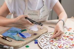 Hands of master working on new modern colorful mosaic. Close-up photo