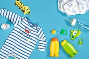 bebé cuidado con bañera colocar. pezón, juguete, ropa, champú en azul antecedentes parte superior ver Bosquejo foto