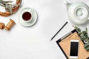 Notepad with pen and cup of tea on white table. Working space. Handmade. Top view, flat lay. photo