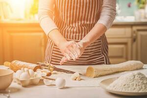 Woman bake pies. Confectioner makes desserts. Making buns. Dough on the table. Knead the dough. photo