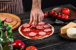 cocinar en el cocina poniendo el ingredientes en el Pizza. Pizza concepto. producción y entrega de alimento. foto