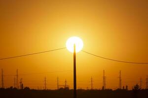 electrical pole against sun at sunset photo