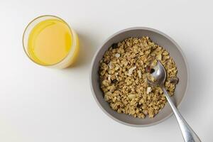 A bowl of granola and a glass of orange juice on white background photo