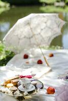 Boda mesa ajuste en el parque. Boda pastel, macarrones, taza de café y blanco sombrilla. foto