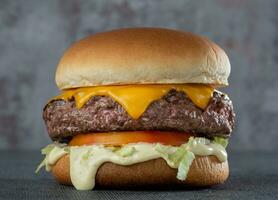 carne de vaca hamburguesa con queso, tomate y lechuga en un negro antecedentes foto