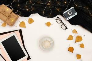 Autumn concept, dried fall leaves, mug of cocoa, old camera, scarf and tablet with blank screen. Mock up photo