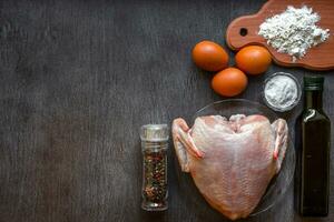 Whole raw chicken with spices on a wooden table photo