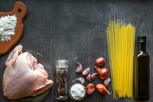 pasta ingredientes. pollo pechos, espaguetis pasta, aceite, especias y ajo en el de madera mesa. espacio para texto. foto
