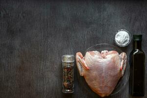 Whole raw chicken with spices on a wooden table photo