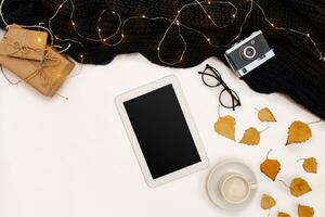 Autumn concept, dried fall leaves, mug of cocoa, old camera, scarf and tablet with blank screen. Mock up photo