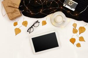 Autumn concept, dried fall leaves, mug of cocoa, old camera, scarf and tablet with blank screen. Mock up photo