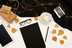 Autumn concept, dried fall leaves, mug of cocoa, old camera, scarf and tablet with blank screen. Mock up photo