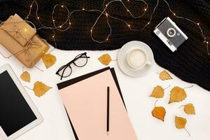 Romantic autumn mock up. Sheet of pink paper, yellow and orange leaves, pencils, cup of cappuccino and old camera.Top view. Flat lay. photo