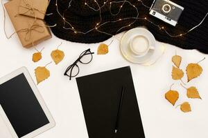 Autumn concept, dried fall leaves, mug of cocoa, old camera, scarf and tablet with blank screen. Mock up photo