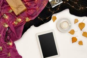Autumn concept, dried fall leaves, mug of cocoa, old camera, scarf and tablet with blank screen. Mock up photo