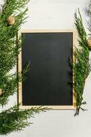 Juniper branches with a Christmas decor. Christmas, New Year background. Coniferous branches of juniper and black writing board. Top view, flat design. photo