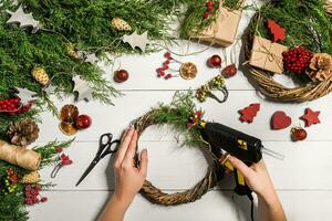 Christmas handmade diy background. Making craft xmas wreath and ornaments. Top view of white wooden table with female hands. photo