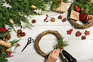 Christmas handmade diy background. Making craft xmas wreath and ornaments. Top view of white wooden table with female hands. photo