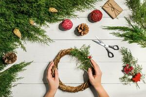 Christmas handmade diy background. Making craft xmas wreath and ornaments. Top view of white wooden table with female hands. photo