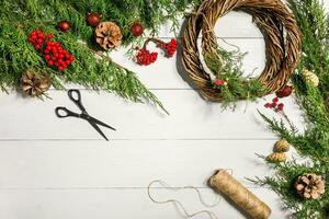 hacer un Navidad guirnalda con tu propio manos. abeto rama, Navidad guirnalda y regalos en un blanco de madera antecedentes foto