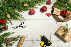 Make a Christmas wreath with your own hands. Spruce branch, Christmas wreath and gifts on a white wooden background photo