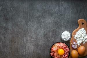 Raw minced meat with egg yolk, wooden cutting board on wooden background photo