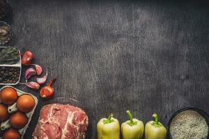 Raw pork meat on a dark wooden surface and ingredients for cooking. Food background with copy space. photo