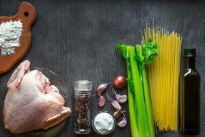 Pasta ingredients. Chicken breasts, oil, spaghetti pasta, elery, spices and garlic on the wooden table. Space for text. photo