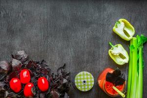 Spicy tomato drink with celery and pepper. Tomato drink in jar surrounded of fresh vegetables on a wooden table photo