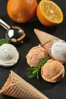 Close-up shot of a creamy and orange ice cream served on a dark slate, black background. photo