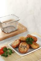 fried potato cheese balls croquettes with tomato ketchup served in a basket. white background and garnish photo