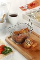 fried potato cheese balls croquettes with tomato ketchup served in a basket. white background and garnish photo