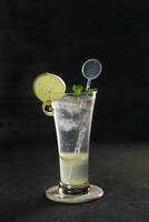 Lemon slush in tall glass with fruit and crushed ice around it on white table with isolated background. Front view. Horizontal composition. photo