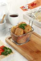 fried potato cheese balls croquettes with tomato ketchup served in a basket. white background and garnish photo