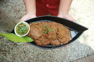 Beef Rendang is a Minang dish originating from the Minangkabau region in West Sumatra, Indonesia. Rendang has been slow cooked and braised in a coconut milk seasoned with a herb and spice mixture photo