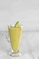 Avocado juice with avocado pieces. served in a very luxurious clear glass. isolated in white background photo