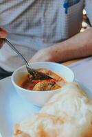 people eating chicken curry, kerala style chicken curry using fried coconut in traditional way and arranged in a black ceramic vessel which is placed on a graphite sheet photo