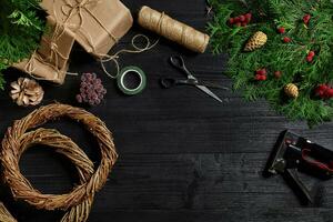 Make a Christmas wreath with your own hands. Spruce branch, Christmas wreath and gifts on a black wooden background photo