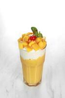 yellow mango juice with garnish of mango pieces, cherries and mint leaves. with a white background and dark wood photo