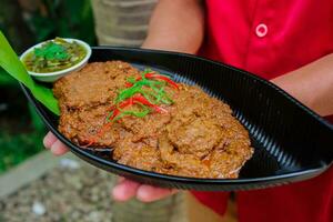 carne de vaca rendang es un minang plato originario desde el minangkabau región en Oeste Sumatra, Indonesia. rendang tiene estado lento cocido y cocido a fuego lento en un Coco Leche sazonado con un hierba y especia mezcla foto