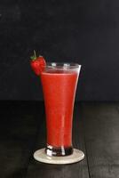 fresa jugo bebida en un claro vaso con fresa guarnación. aislado en blanco y oscuro antecedentes foto