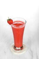 Strawberry juice drink in a clear glass with strawberry garnish. isolated on white and dark background photo