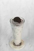 milkshake with whipped cream and biscuits served in glass on the light gray table. isolated in white and dark wood background photo