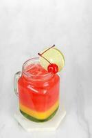 Strawberry juice drink in a clear glass with gradation in the glass and cherry garnish. isolated on white and dark background photo