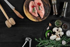 Raw chicken breast fillets on wooden cutting board with herbs and spices. Top view with copy space photo