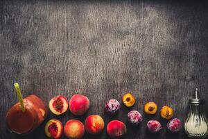 Peach and plums fruits smoothie in glass bottle and straws on wooden table. Healthy lifestyle. Toned photo